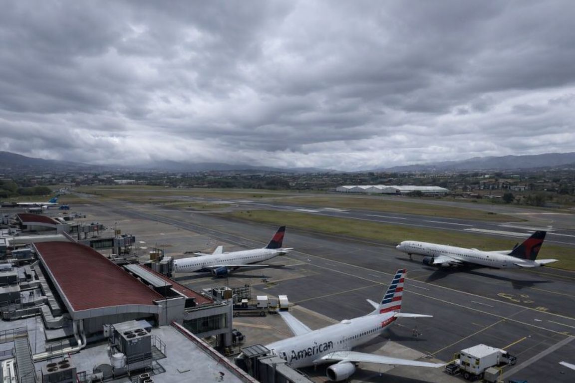 Juan Santamaría International Airport runway with multiple airplanes and terminal in San José, captured during a tour with Corcovado National Park Tours